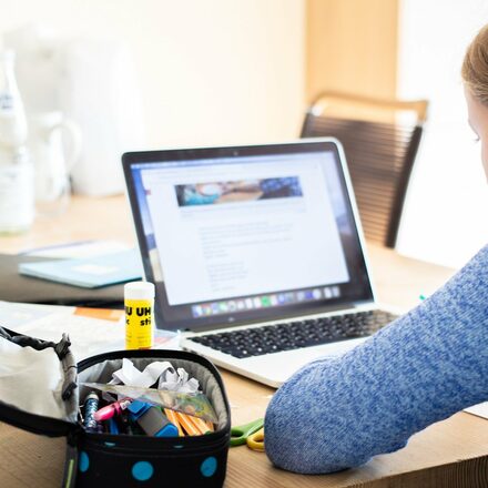 Ein Mädchen sitzt vor einem Laptop und lernt.