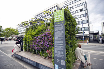 Ein mobiles Grünes Zimmer, ein Plateau mit Sitzmöglichkeiten und senkrecht wachsenden Pflanzen, steht in der Stadt.