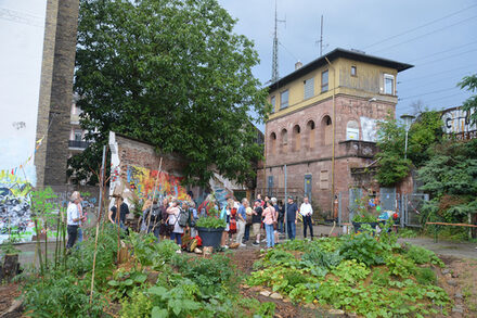 Eine Gruppe Menschen geht zwischen einem Garten und einem Gebäude am Hauptbahnhof entlang.