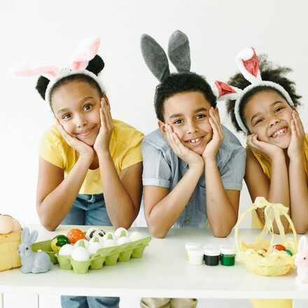 drei Kinder mit Hasenohren und Ostereiern