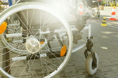 Ein Rollstuhl ist auf dem Bürgersteig geparkt.