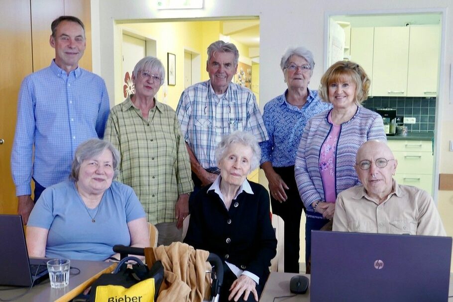 Das Bild zeigt eine Gruppe Senioren. Im Vordergrund sieht man einen Laptop.