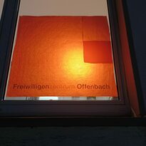 Ein Fenster vom Freiwilligenzentrum Offenbach ist orange beleuchtet.