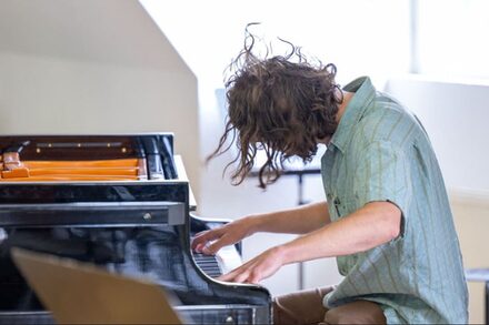 Zu sehen ist ein Pianist beim Spielen des Instruments