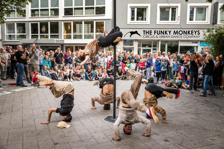 The Funky Monkeys performen in einer Fußgängerzone und viele Menschen schauen zu