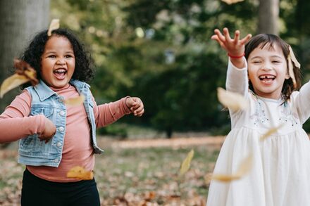Zwei kleine Mädchen rennen fröhlich durch den Wald.