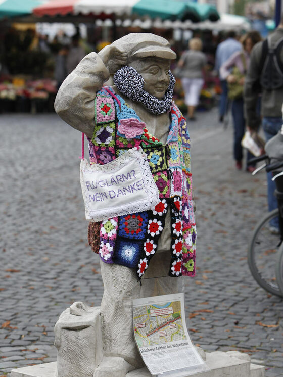 Statue Streichholz Karlchen mit Umhängetasche "Fluglärm? Nein danke"