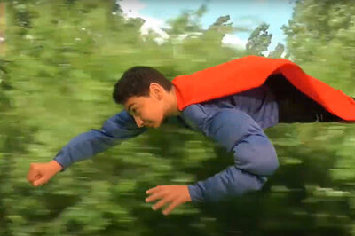 Ein Kind mit rotem Cape fliegt durch die Luft.