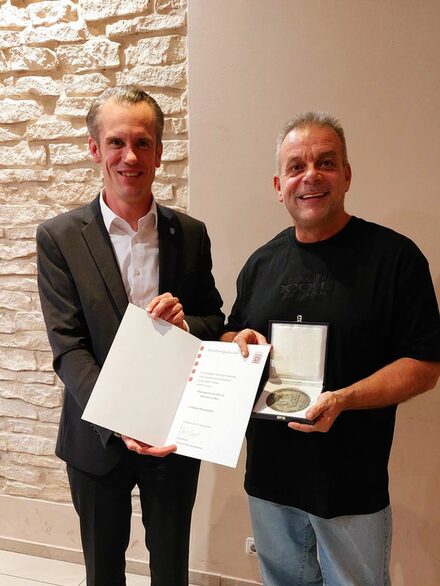 Oberbürgermeister Dr. Felix Schwenke hat die Urkunde in der Hand, daneben Peter Ortwein mit der silbernen Ehrenplakette.