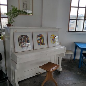 Ein Stuhl steht vor einem Klavier, auf dem drei Bilder stehen.