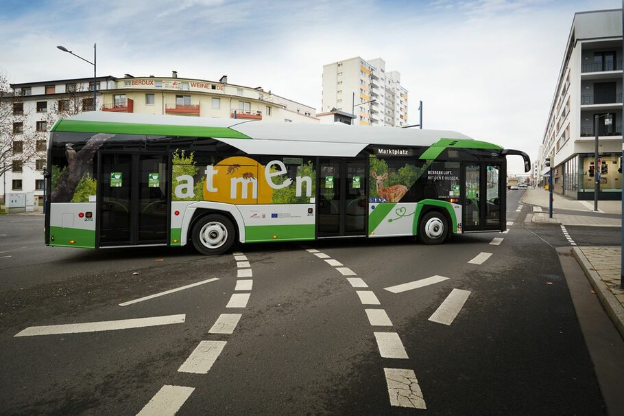 Ein grün-weißer E-Bus biegt um die Kurve.