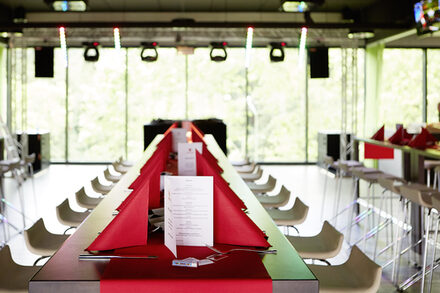 Ein langer Tisch mit roten Servietten und roter Tischdecke.