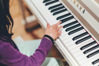 Kind spielt am Klavier, nur der Arm ist zu sehen